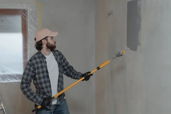 Painter rolling grey paint onto an interior wall in Lubbock